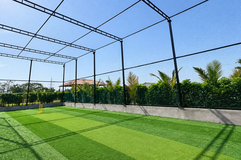Enclosed cricket turf with green playing surface and net structure — AI recreation from supplied reference
