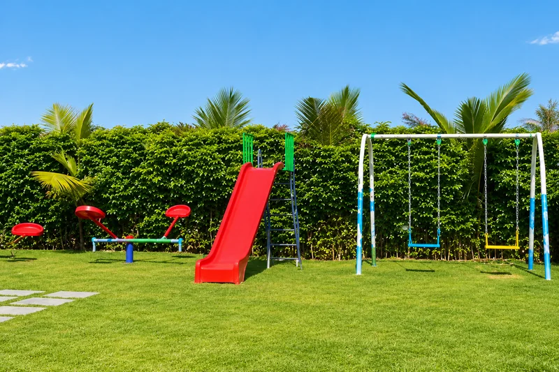 Red slide and swings in the outdoor kids play area — AI recreation from supplied reference